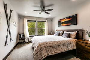 Carpeted bedroom featuring ceiling fan and a textured ceiling