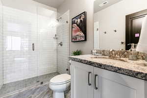 Bathroom with tile floors, a shower with door, vanity, and toilet