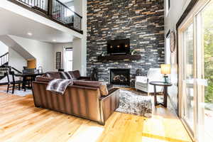 Living room featuring a towering ceiling, light hardwood / wood-style flooring, and a fireplace