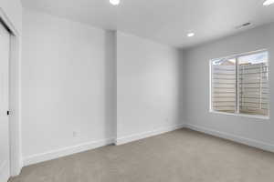 Unfurnished room with a textured ceiling and light carpet