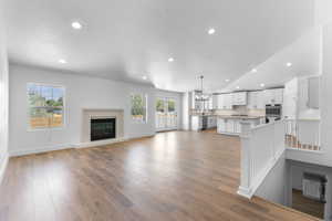 Unfurnished living room with light wood-type flooring, a wealth of natural light, sink, and a notable chandelier