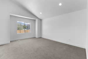 Carpeted empty room with a textured ceiling and vaulted ceiling