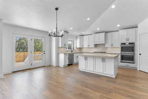 Kitchen featuring a center island, stainless steel appliances, white cabinets, and light hardwood / wood-style floors