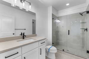 Bathroom with vanity, toilet, an enclosed shower, and tile patterned floors