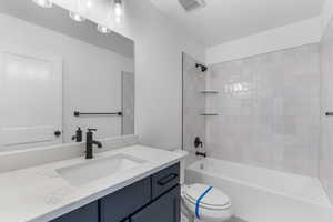 Full bathroom featuring tiled shower / bath, toilet, a textured ceiling, and vanity