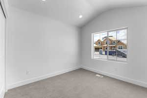 Empty room with lofted ceiling and carpet