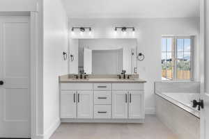 Bathroom featuring tiled tub, vanity, and tile patterned flooring