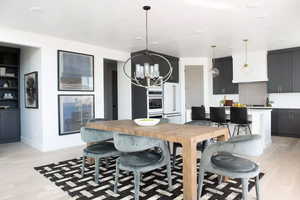 Kitchen featuring light hardwood / wood-style floors, a notable chandelier, hanging light fixtures, tasteful backsplash, and a breakfast bar