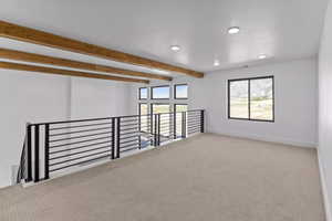 Unfurnished room featuring beam ceiling and carpet flooring