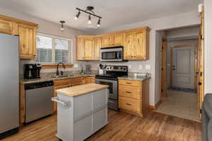 Kitchen featuring rail lighting, tile flooring, a center island, appliances with stainless steel finishes, and sink