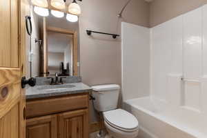 Full bathroom with tile floors, toilet, bathing tub / shower combination, and vanity with extensive cabinet space