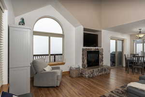 Living room with high vaulted ceiling, dark wood-type flooring, and a fireplace
