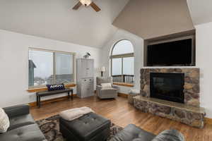 Living room with a fireplace, high vaulted ceiling, ceiling fan, and hardwood / wood-style floors