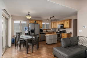 Kitchen with a kitchen island, stainless steel appliances, hanging light fixtures, rail lighting, and light wood-type flooring