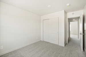 Unfurnished bedroom featuring a closet and light colored carpet