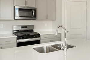 Kitchen with sink, appliances with stainless steel finishes, and white cabinetry