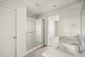 Bathroom featuring dual vanity, an enclosed shower, and wood-type flooring