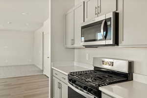 Kitchen featuring white cabinetry, light carpet, and stainless steel appliances