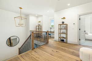 Hall featuring an inviting chandelier and light hardwood / wood-style flooring and loft