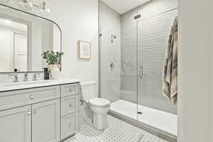 Bathroom featuring tile flooring, an enclosed shower, toilet, and vanity