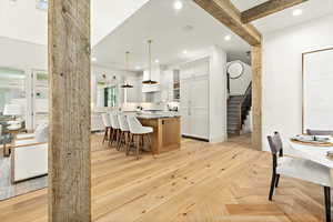 Kitchen with white cabinetry, a kitchen island, a breakfast bar area, decorative light fixtures, and light parquet floors