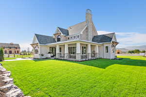 Rear view of house with a mountain view, a yard, and covered porch