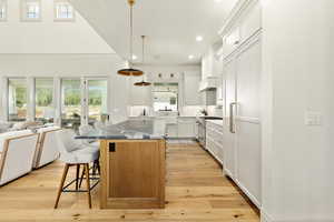 Kitchen featuring high end stainless steel range, a kitchen breakfast bar, a kitchen island, light hardwood / wood-style flooring, and white cabinets