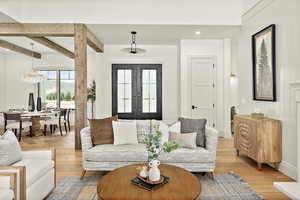 Living room featuring a notable chandelier, beam ceiling, french doors, and light hardwood / wood-style floors