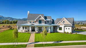 View of front of house with a mountain view, a front yard, and covered porch