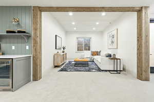 lower level Living room featuring beamed ceiling, light carpet, and beverage cooler