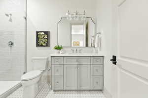 Bathroom with tile flooring, tiled shower, toilet, and large vanity