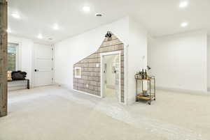 Bonus room featuring light colored carpet and under stair play area