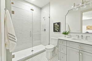 Bathroom featuring walk in shower, tile flooring, vanity with extensive cabinet space, and toilet