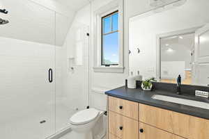 Accessory Apartment Bathroom with vaulted ceiling, vanity, toilet, and a shower with door