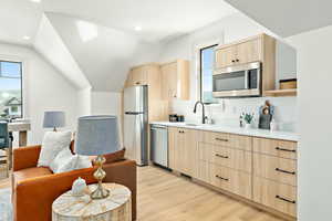 Accessory Apartment Kitchen featuring light hardwood / wood-style floors, stainless steel appliances, light brown cabinetry, sink, and lofted ceiling