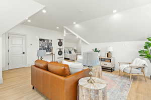 Accessory Apartment Living room featuring stacked washer / dryer, vaulted ceiling, and light hardwood / wood-style flooring