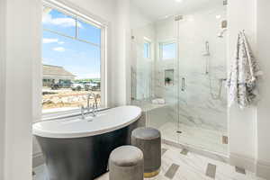 Primary Bathroom featuring tile floors, a healthy amount of sunlight, and separate shower and tub