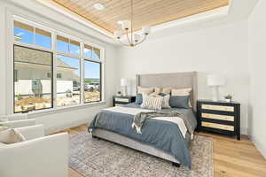 Primary Bedroom with an inviting chandelier, light hardwood / wood-style floors, a raised ceiling, and wood ceiling