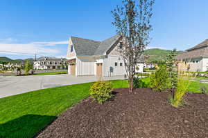 View of side of home featuring a lawn and a garage