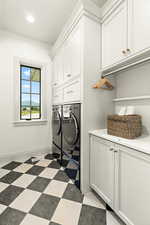 Laundry room with cabinets, tile flooring, and washer and clothes dryer