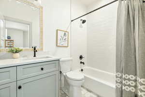 Full bathroom featuring shower / bath combination with curtain, toilet, tile floors, and large vanity