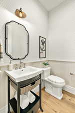 Bathroom with hardwood / wood-style floors, toilet, and large vanity