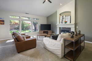 Carpeted living room featuring high vaulted ceiling and ceiling fan