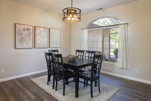 Dining space featuring a notable chandelier and dark wood-type flooring