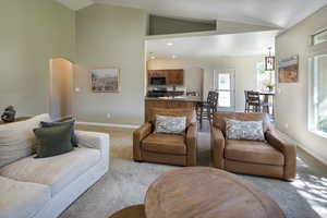 Carpeted living room featuring sink and vaulted ceiling