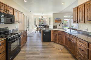 Kitchen with plenty of natural light, sink, hardwood / wood-style floors, and black appliances