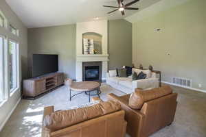 Carpeted living room with ceiling fan and lofted ceiling