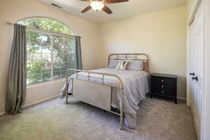 Carpeted bedroom with ceiling fan and a closet