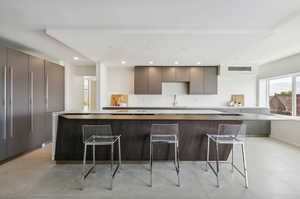 Kitchen with a breakfast bar, sink, a kitchen island, and light tile floors