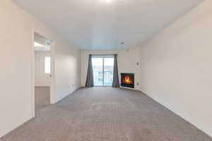 Unfurnished living room with a textured ceiling and carpet floors